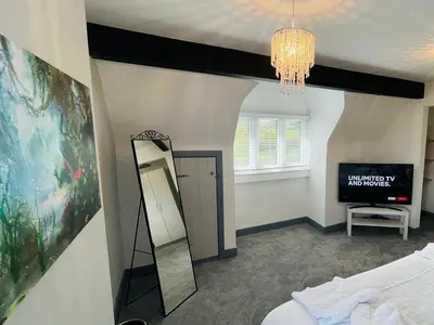 a bedroom with a mirror and a bed and a chandelier at Warren Lodge in Little Baddow