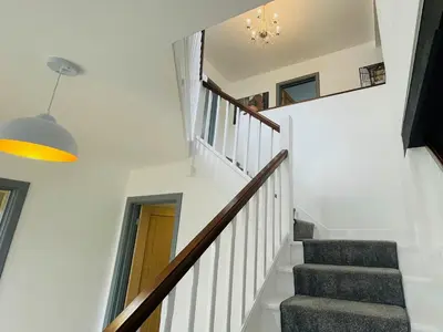 a staircase in a house with white walls and a hallway at Warren Lodge in Little Baddow