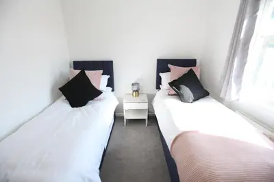 two twin beds in a room with a side table at Stylish Cambridge City Pad in Chesterton