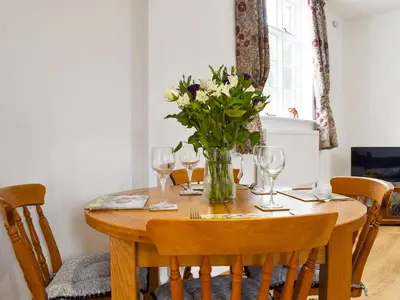 a table with a vase of flowers and wine glasses at Fallow Cottage - Uk33488 in Hadleigh