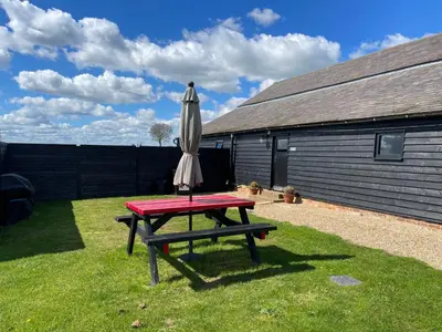 a picnic table with an umbrella and a picnic table at The Cow Shed - Sleeps 4 Parking & Pet Friendly in Bradwell on Sea