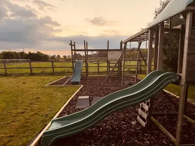 a playground with a slide in a field at Alfie Acres - Secluded Cabin set in 5 Acres of Privacy, with Exclusive use of Swimming Pool and Hot Tub for up to 10 Guests in Downham