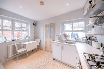 a kitchen with white cabinets and a sink and windows at 6 West Lane in Aldeburgh - Beautiful cottage near high street in Aldeburgh