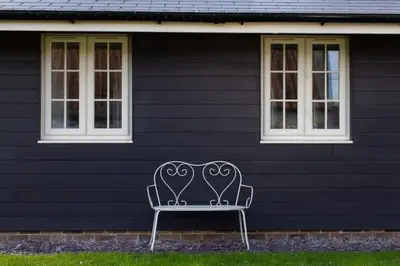 a bench sitting in front of a black house at Breckland Cottage - Secluded Country Getaway in Hockwold cum Wilton