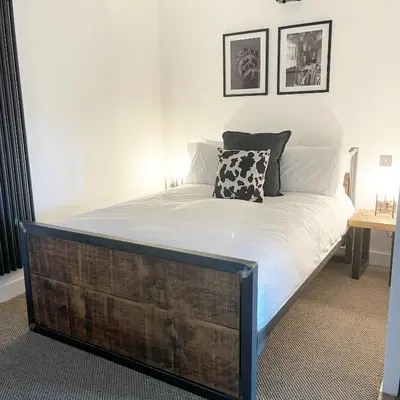 a bed with a wooden frame in a bedroom at Booking Urban Halstead in Halstead