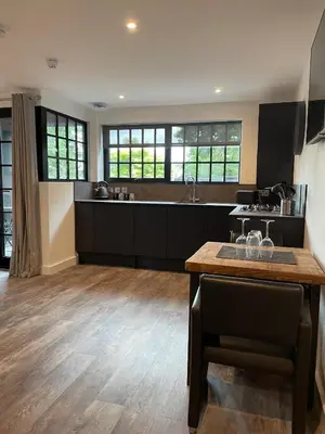 a large kitchen with black cabinets and a wooden floor at Booking Urban Halstead in Halstead