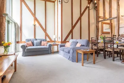a living room with two blue couches and a table at Granary Cottage, Valley Farm, Snape in Saxmundham