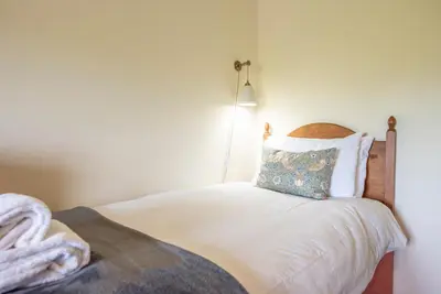 a bedroom with a bed with a pillow and a lamp at Granary Cottage, Valley Farm, Snape in Saxmundham