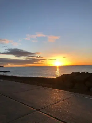 a sunset over the ocean with the sun setting at Tref y Clawdd in Felixstowe