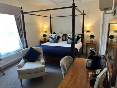 a bedroom with a canopy bed and a chair and a table at Slepe Hall Hotel in St Ives
