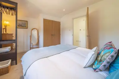 a bedroom with a large white bed and a mirror at Yew Tree Cottage in Westleton