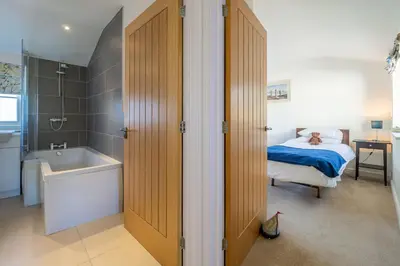 a bedroom with a bed and a tub and a sink at Yew Tree Cottage in Westleton