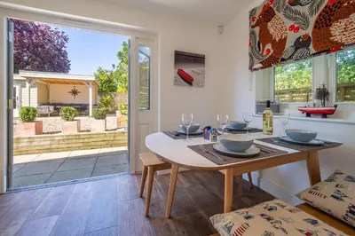 a dining room with a table and a glass door at Yew Tree Cottage in Westleton