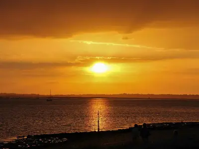 people standing on the beach watching the sunset at Curlew in Brightlingsea