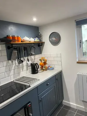 a kitchen with a counter and a clock on the wall at Foxgloves self catering in Westleton