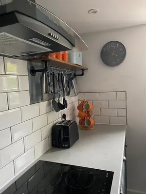 a kitchen with a microwave and a clock on the wall at Foxgloves self catering in Westleton