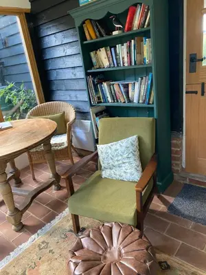 a room with a table and chairs and a book shelf at Foxgloves self catering in Westleton