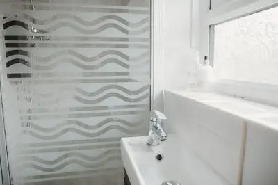 a white bathroom with a shower and a sink at Hazel's in Leiston