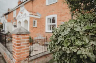 a brick building with a fence and a bush at Hazel's in Leiston
