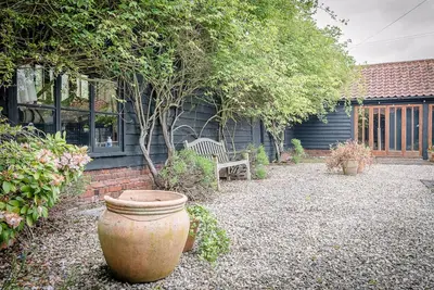a garden with a large pot and a bench in front of a house at The Hayloft, Clopton in Clopton