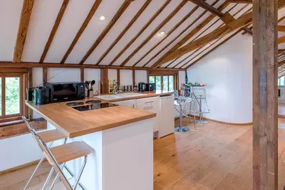 a kitchen with white counters and wooden ceilings at The Hayloft, Clopton in Clopton