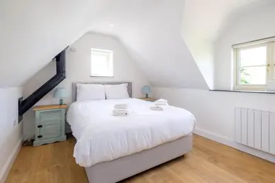 a bedroom with a white bed and a window at Foxes Lodge in Aldringham