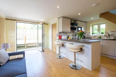 a kitchen and living room with a blue couch at Foxes Lodge in Aldringham