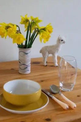 a table with a bowl and a vase with yellow flowers at 2 Bed in Weybread oc-tclwey in Needham