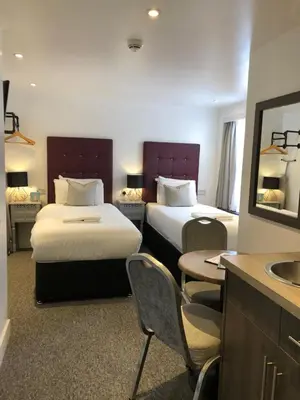 a hotel room with two beds and a sink at Kings Hotel in Newmarket
