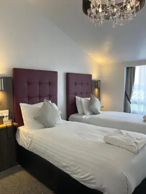 a hotel room with two beds and a chandelier at Kings Hotel in Newmarket