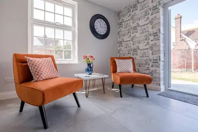 two chairs and a table in a room with a clock at The Grange, Aldeburgh in Aldeburgh