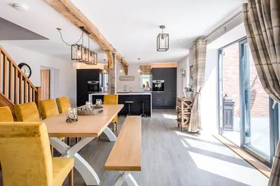a kitchen and dining room with a wooden table and yellow chairs at Chapel Cottage at Pond Hall Farm, Stunnning Property with Private Hot Tub, Hadleigh in Ipswich