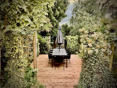a table with chairs and an umbrella in a garden at Mill House Townhouse in Newmarket