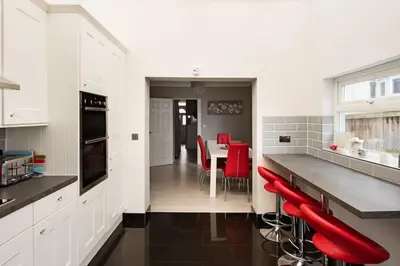 a kitchen with red chairs and a table in it at A Wave From It All in Great Clacton