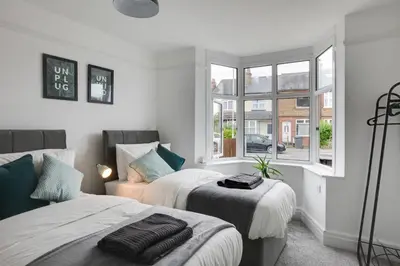 a bedroom with two beds and a window at Spacious Three Bedroom House - Free Parking & Wifi in Chelmsford