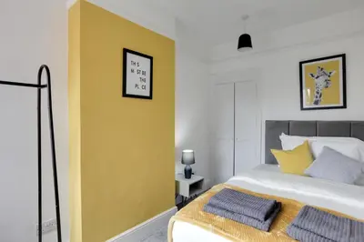a bedroom with a yellow accent wall and a bed at Spacious Three Bedroom House - Free Parking & Wifi in Chelmsford
