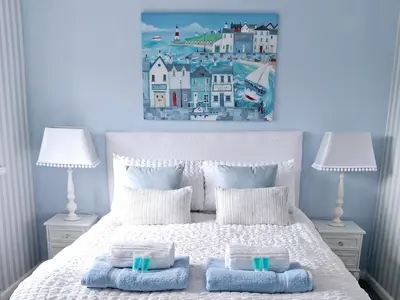 a bedroom with a bed with two lamps and a painting on the wall at HOME from HOME GUEST HOUSE in Rochford
