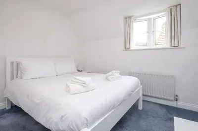 a white bed in a white room with a window at Bryony Cottage, 3 bedroom house in the seaside town of Aldeburgh - Aldeburgh Coastal Cottages in Aldeburgh
