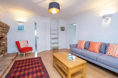 a living room with a blue couch and a red chair at Bryony Cottage, 3 bedroom house in the seaside town of Aldeburgh - Aldeburgh Coastal Cottages in Aldeburgh