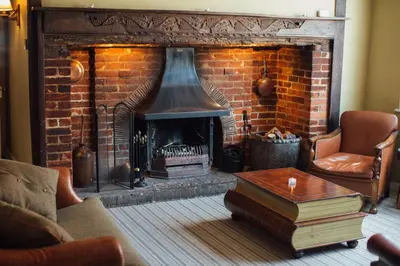 a living room with a brick fireplace and a table at The Marlborough Dedham in Dedham