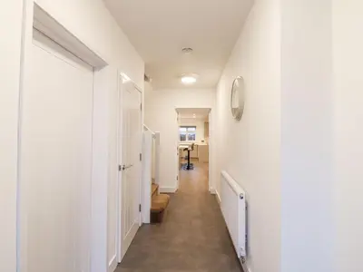 a hallway with white walls and a clock on the wall at Exning Residence in Newmarket