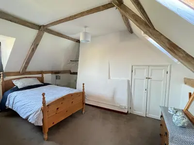 a bedroom with a wooden bed in a attic at Dairy Cottage in Cockley Cley
