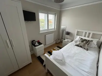 a bedroom with a white bed and a television at Magnolia House in Royston