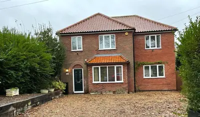 a brown brick house with white windows and a driveway at Number 15 in Norwich