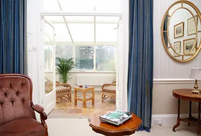 a living room with a chair and a window at Bressingham Hall in Bressingham