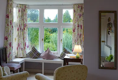 a living room with a large window with pillows at Bressingham Hall in Bressingham