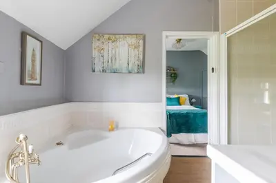 a white bathroom with a tub and a bedroom at The Anchor in Sutton