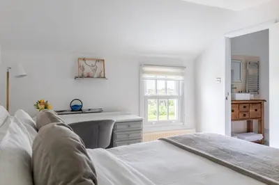 a white bedroom with a bed and a desk at The Anchor in Sutton