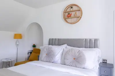 a white bed with white pillows and a mirror on the wall at The Anchor in Sutton