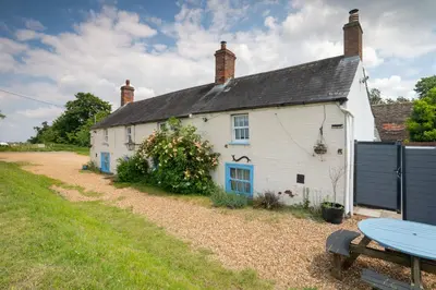 a white cottage with blue windows and a picnic table at The Anchor in Sutton